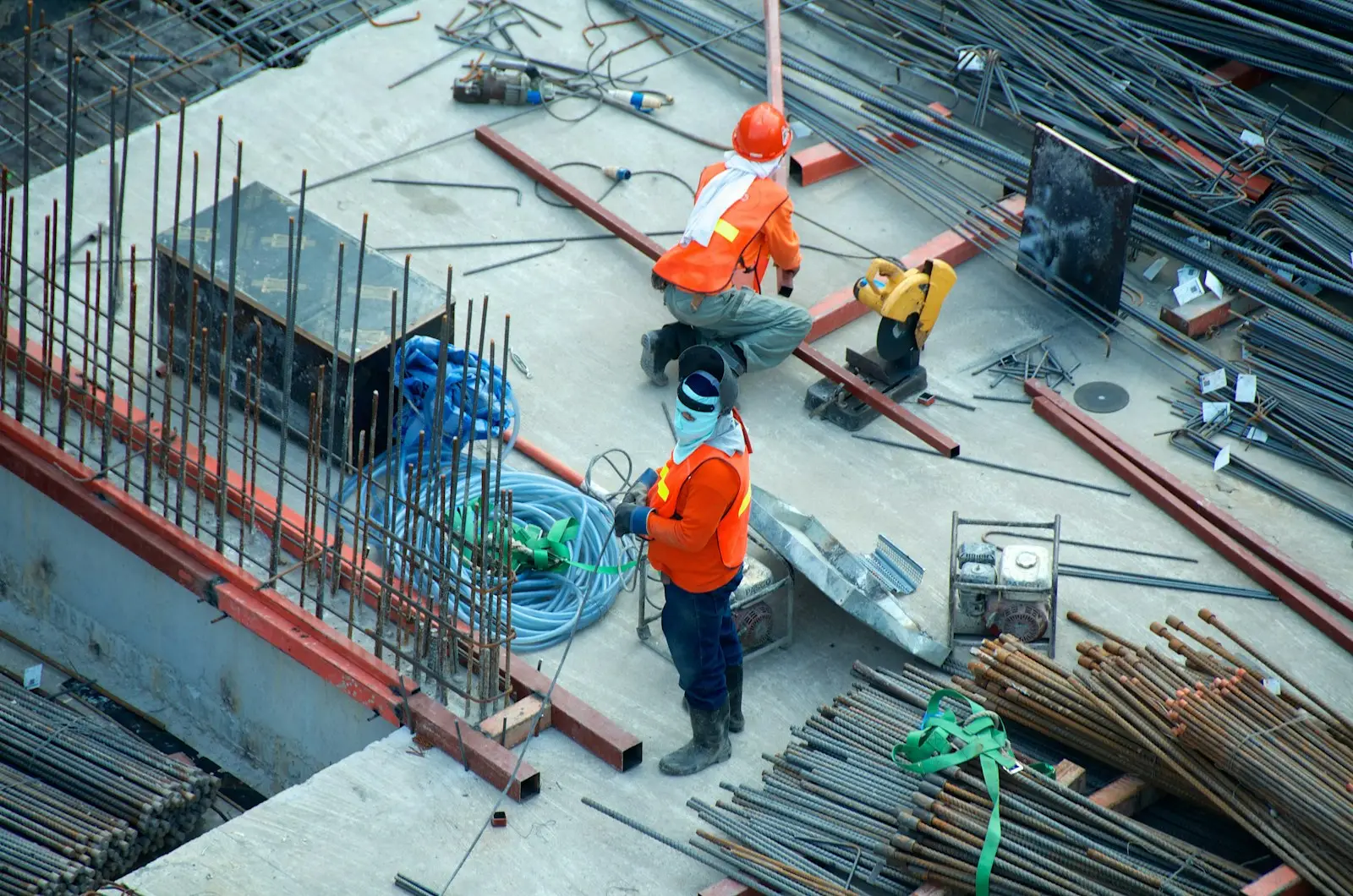 Construction workers in orange hi-vis working among rebar on a concrete deck
