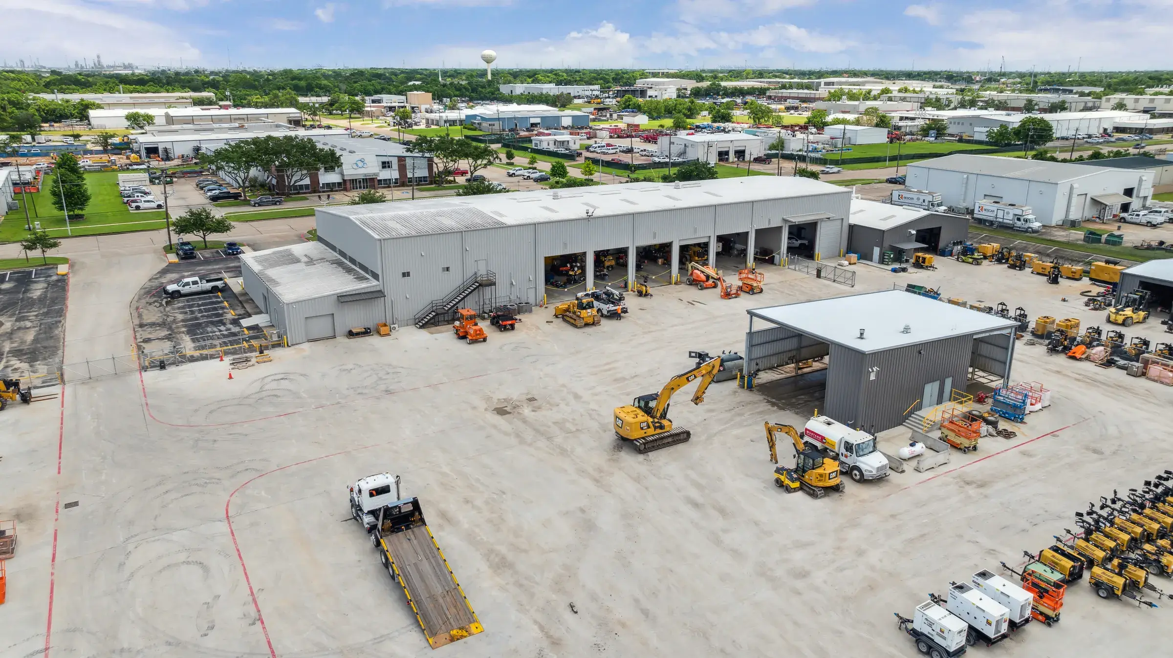 Aerial view of the Mustang CAT Deer Park facility in operation — open service bays along the building with trucks and machines working the yard