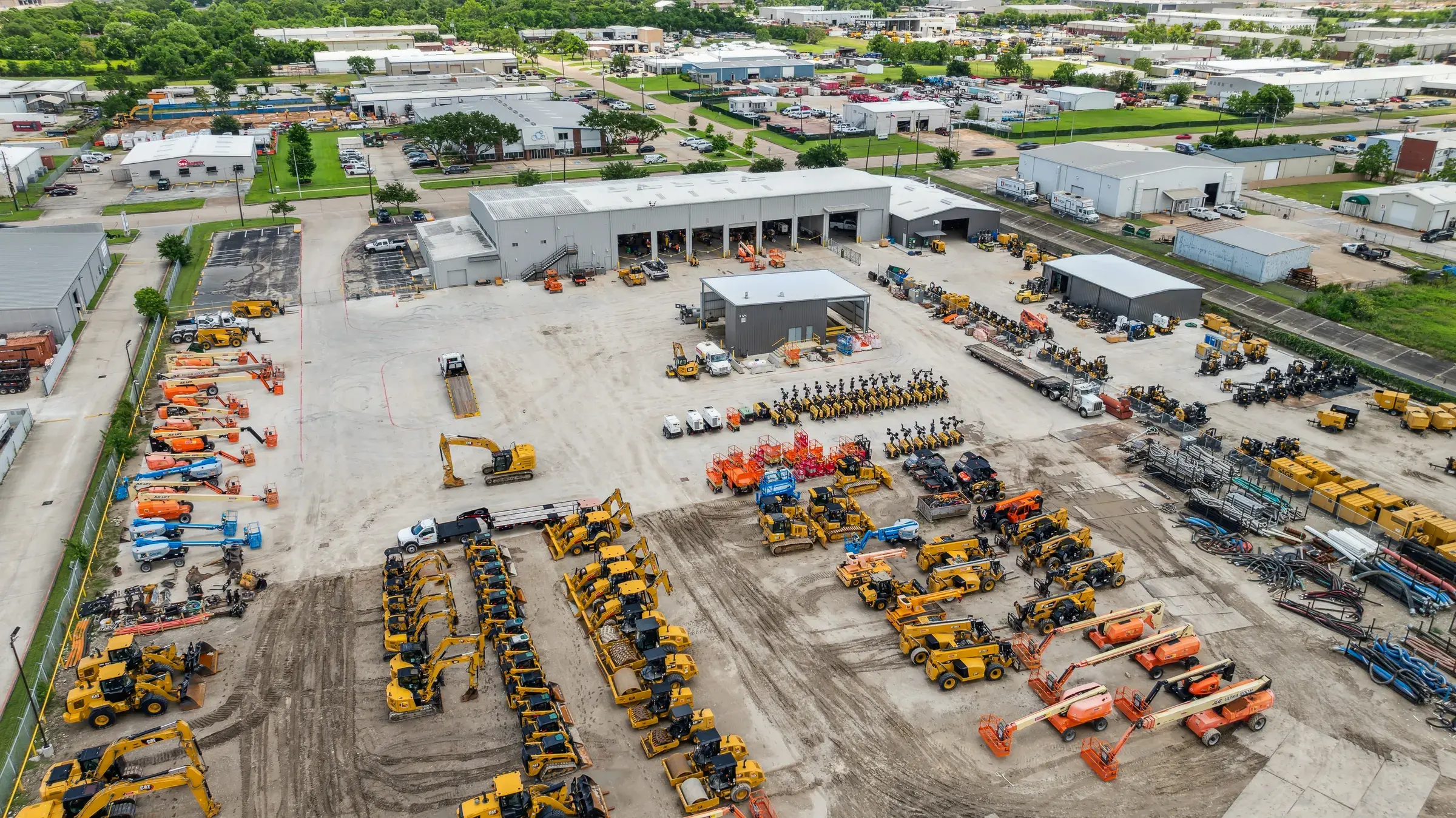 Aerial across the full yard with machines lined up row on row behind the building