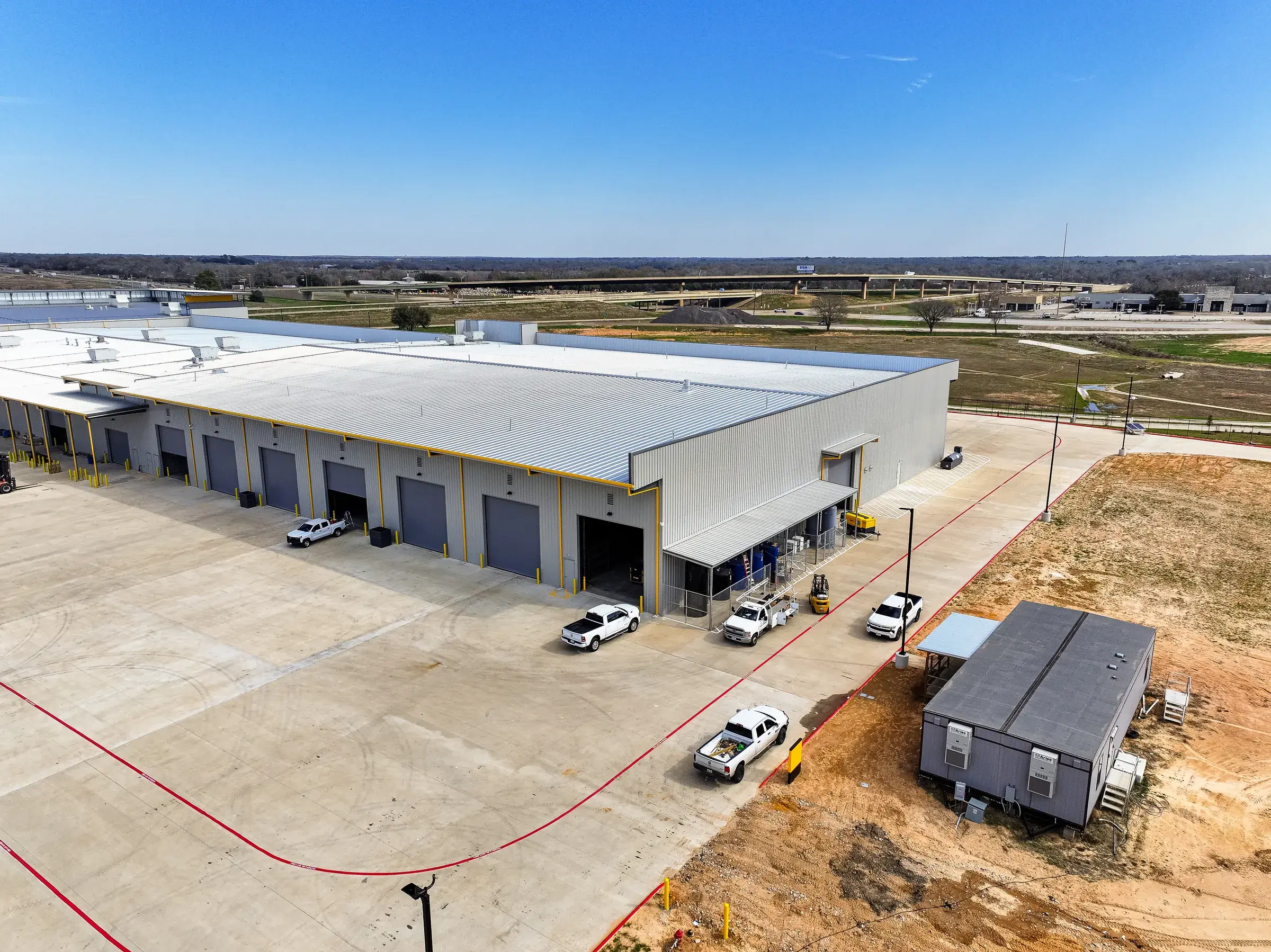 Long elevation of the service building, a row of overhead doors running down the concrete apron