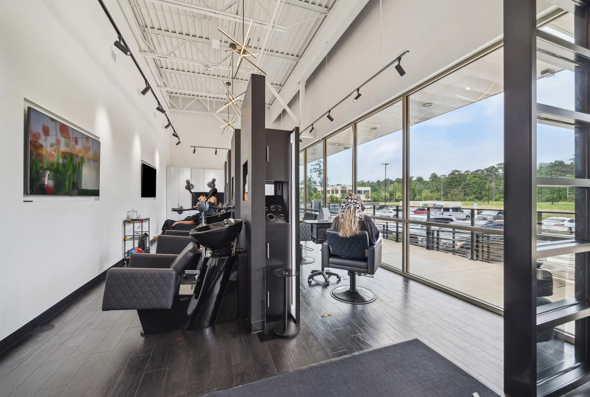 Styling stations and shampoo chairs along the window wall, mirrors facing into the room