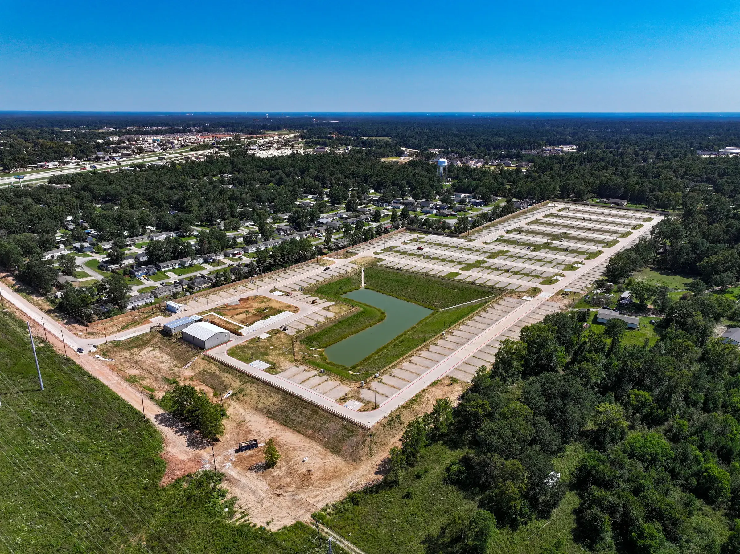 The detention pond in the foreground with the graded slopes and pad rows running back behind it